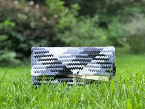 A black and white clutch placed on some grass.