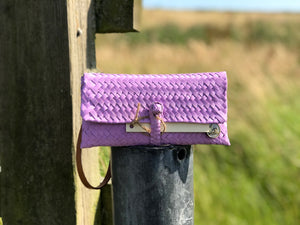 A pink handmade wristlet bag placed in front of a field.