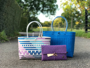 Two handmade bags and a clutch placed in front of a field in the evening.
